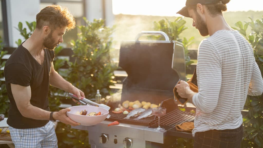 Two guys grilling food in their backyard