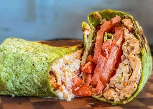 Frazie'S Meat &Amp; Market | Frazie'S Meat &Amp; Market Green spinach wrap filled with shredded chicken, fresh tomatoes, and lettuce, showcasing a gourmet sandwich option from Frazie's Meat & Market in Atlanta.