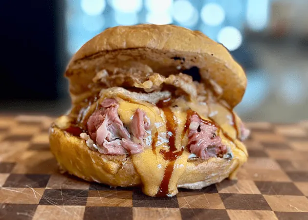 Frazie'S Meat &Amp; Market | Frazie'S Meat &Amp; Market Gourmet sandwich featuring tender, sliced roast beef, melted cheddar cheese, crispy onions, and barbecue sauce, served on a toasted bun, highlighting Frazie's Meat & Market's artisanal offerings.