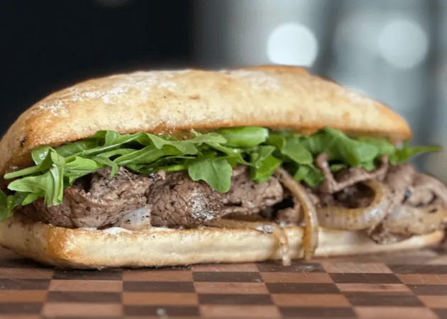 Frazie'S Meat &Amp; Market | Frazie'S Meat &Amp; Market Hand-crafted sandwich featuring tender beef, sautéed onions, and fresh arugula on artisan bread, representing Frazie's Meat & Market's gourmet offerings in Atlanta.
