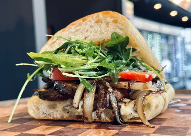 Frazie'S Meat &Amp; Market | Frazie'S Meat &Amp; Market Hand-crafted gourmet sandwich featuring grilled mushrooms, onions, fresh arugula, and tomato on rustic bread, highlighting Frazie's Meat & Market's commitment to high-quality, locally sourced ingredients.
