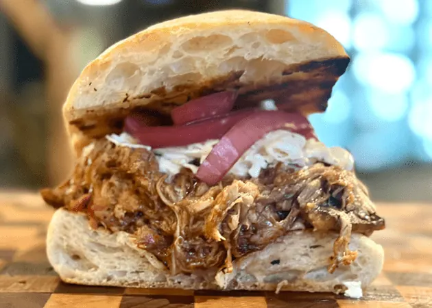 Frazie'S Meat &Amp; Market | Frazie'S Meat &Amp; Market Pulled pork sandwich with coleslaw and pickled onions on a toasted bun, highlighting Frazie's Meat & Market's gourmet offerings in Atlanta.