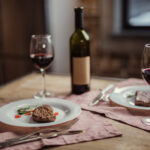 meat and wine pairing - red wine in glass with bottle and two plates with steak