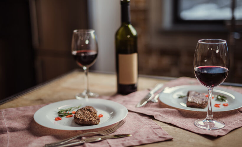 meat and wine pairing - red wine in glass with bottle and two plates with steak